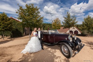 Photographie de mariés avec la voiture qui les a emmené à la réception